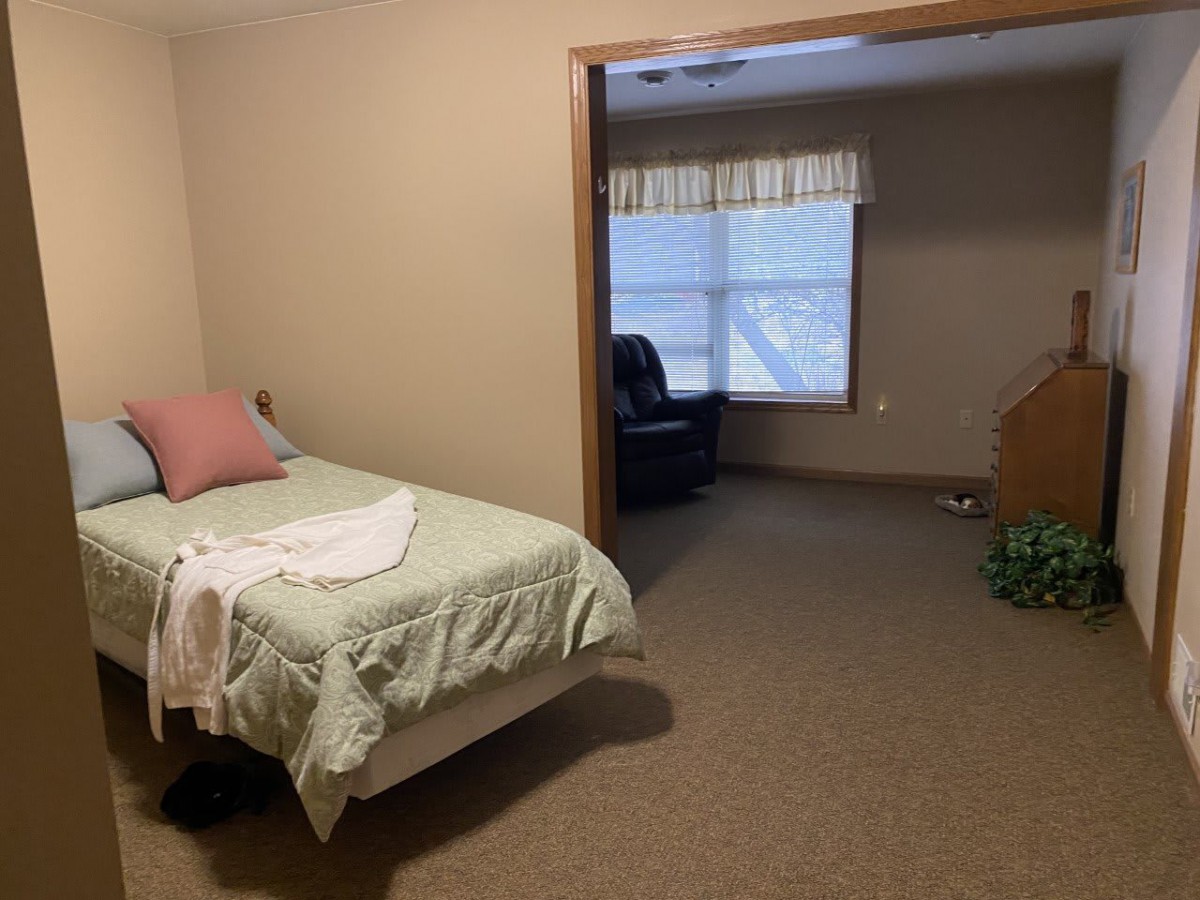 A simple bedroom with a single bed and an armchair by the window.