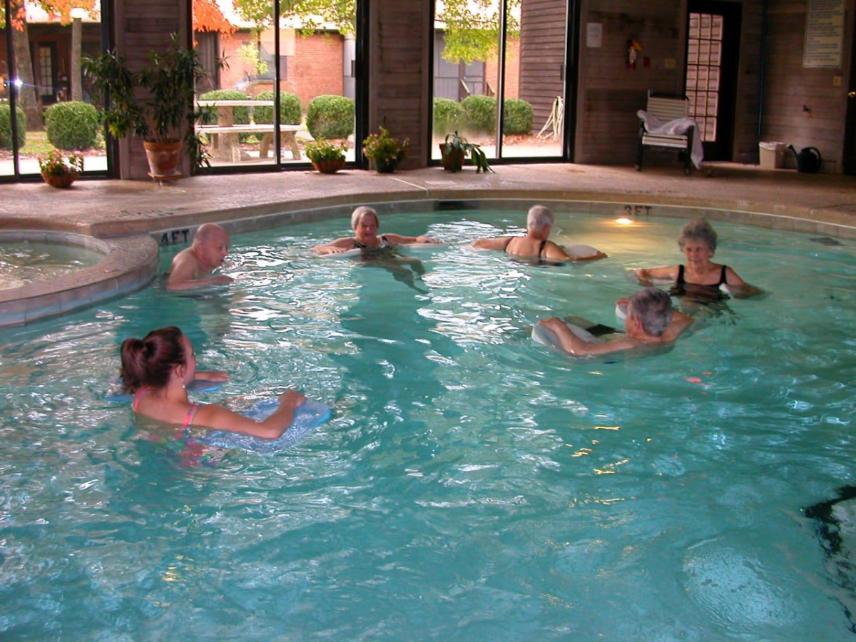 A group of seniors participating in water aerobics in an indoor swimming pool.