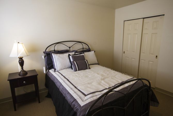 A neatly arranged bedroom with a bed, nightstand, and lamp.