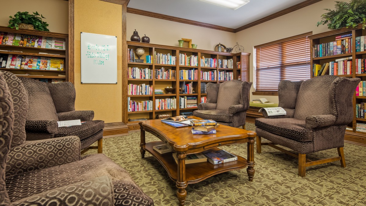 A cozy library room with comfortable seating and bookshelves.