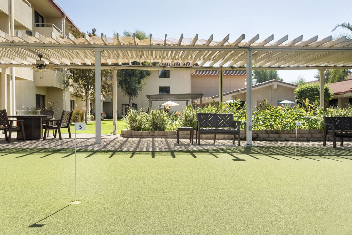 A tranquil outdoor space with a pergola and seating area overlooking a well-maintained lawn.