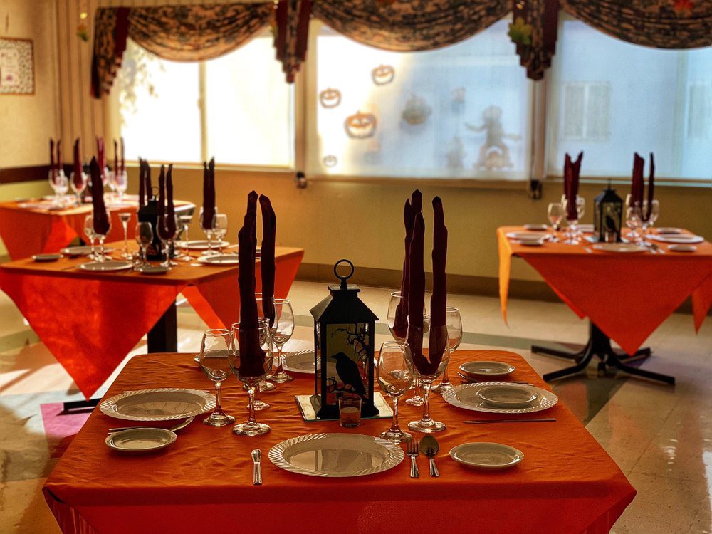 An elegantly set restaurant table with orange tablecloths, ready for a formal dinner.