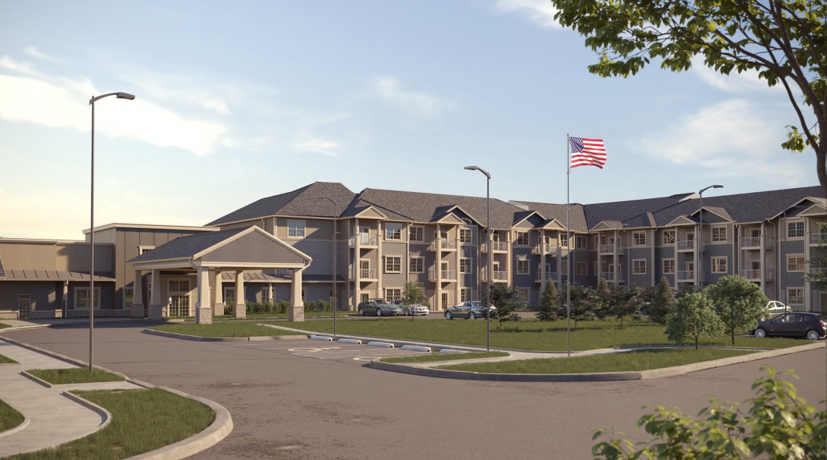 A large residential apartment complex with an American flag flying in front, surrounded by a parking lot.