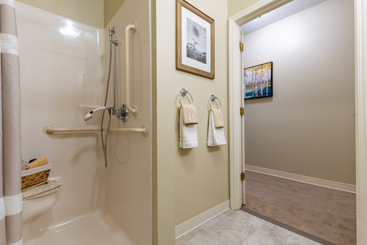 A bathroom featuring a walk-in shower, neatly arranged towels, and framed wall art.