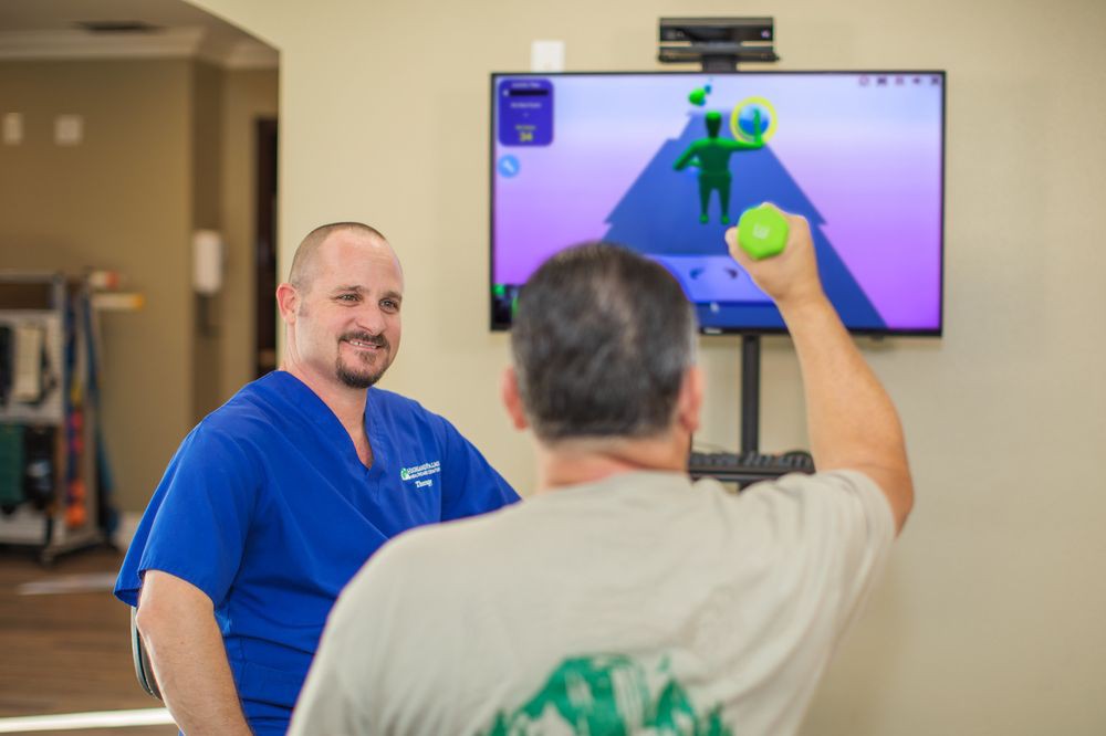 A therapist guides a patient through video game-based physical therapy.