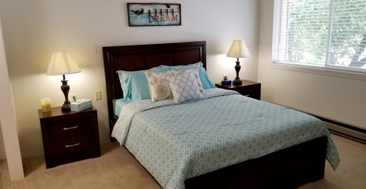 A neatly arranged bedroom with a bed, pillows, and a lamp on the nightstand.