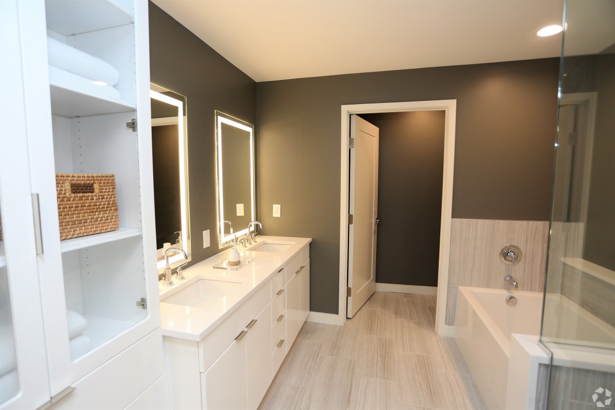 A modern bathroom with dual vanities and illuminated mirrors.