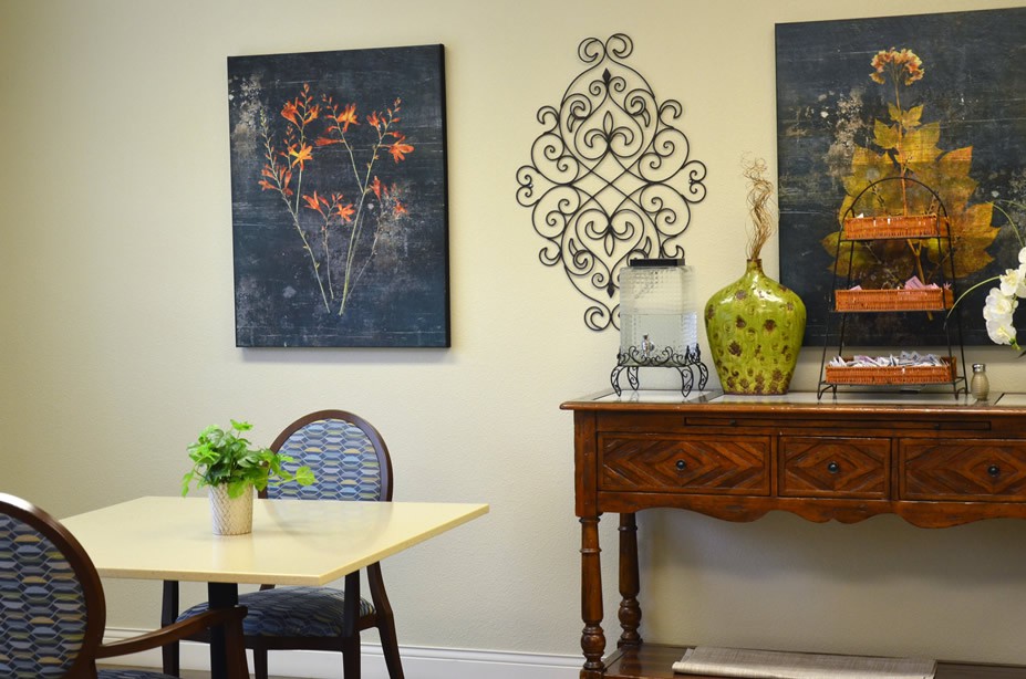 A cozy interior setting featuring a wooden table with a plant, wall art, and decorative items on a console.