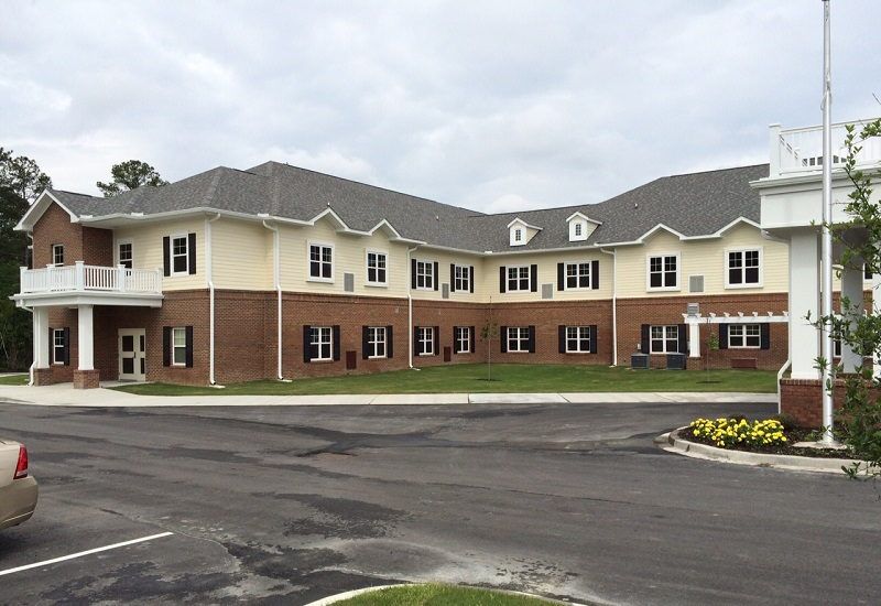 A two-story brick residential building under a cloudy sky.