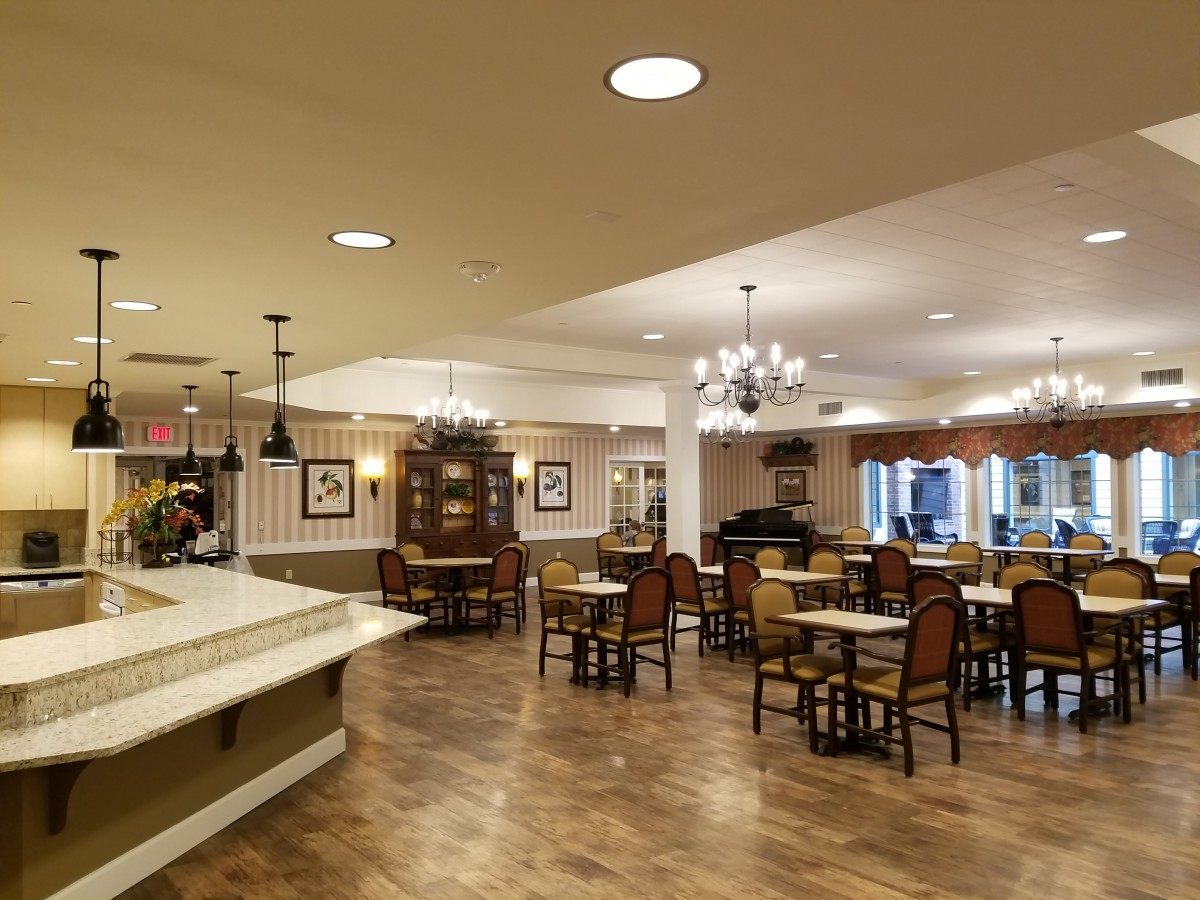 A cozy dining area with tables and chairs, featuring elegant lighting and decor.