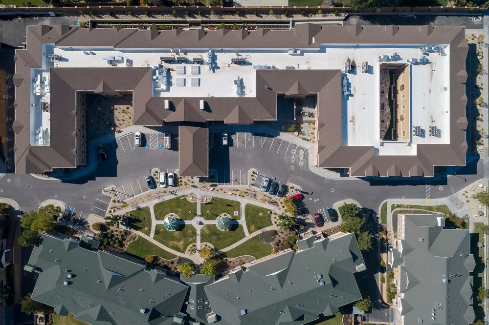 An aerial view of a large building complex featuring a central courtyard with landscaped gardens.