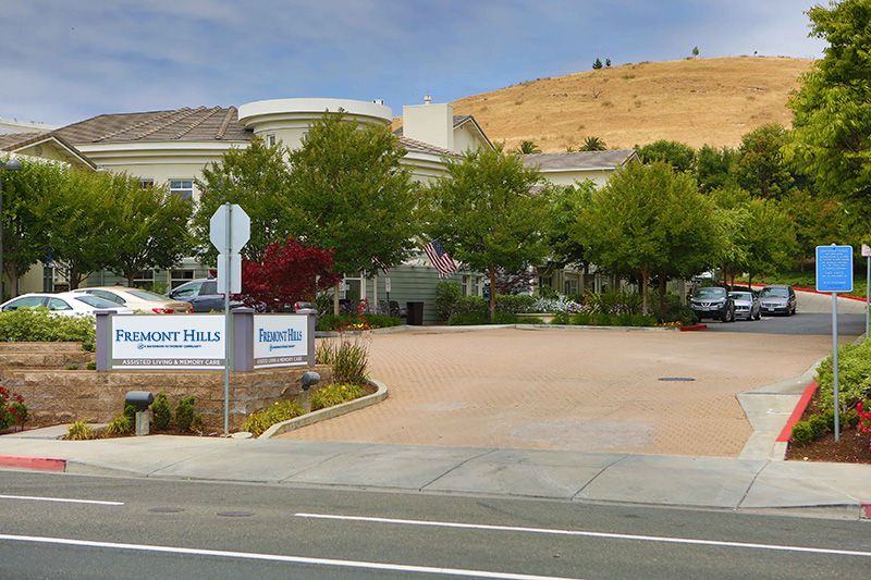 A view of a building with surrounding trees and a parking area.