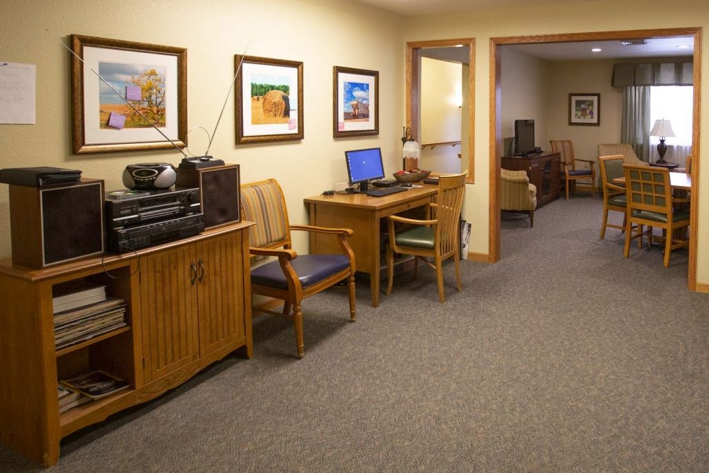 A cozy office interior featuring a computer workstation, chairs, and wall art.