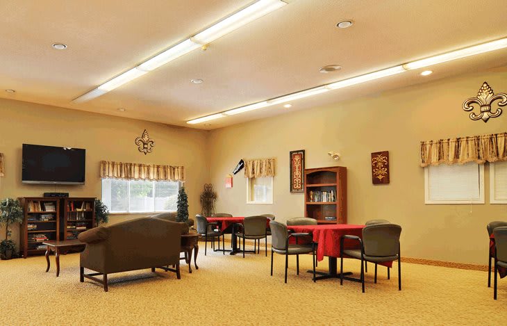 A well-lit room with tables, chairs, and bookshelves decorated in a cozy style.