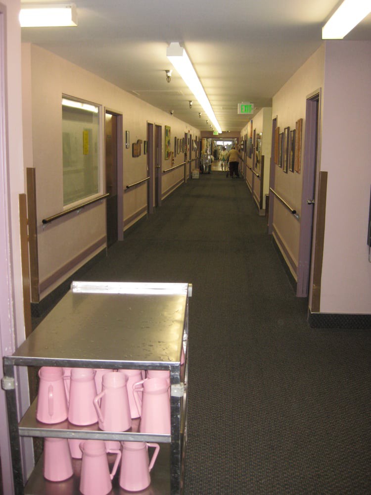 A long corridor with a trolley holding pink cups, likely in a healthcare facility.