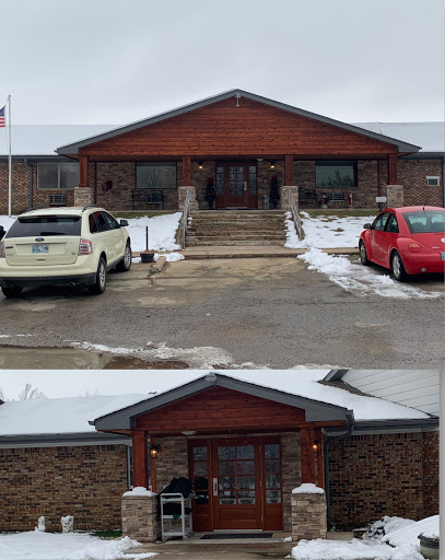 A view of a building's entrance surrounded by snow and parked cars.