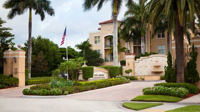 Entrance of a residential building with tropical landscaping and palm trees.