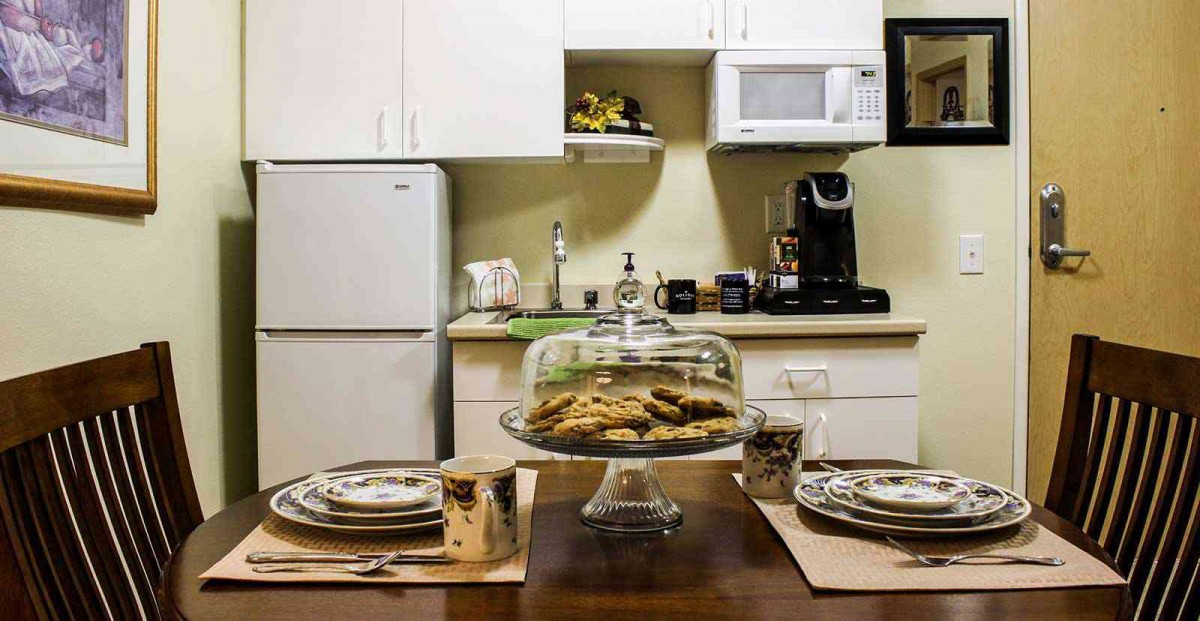 A cozy kitchen setup with freshly baked cookies on a cake stand and a beautifully arranged dining table.