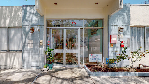 The inviting entrance of a modern building, showcasing glass doors and potted plants.
