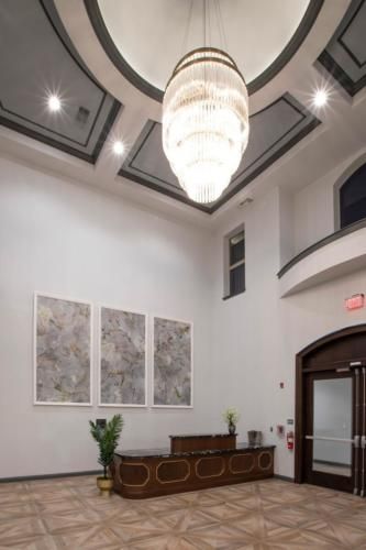 A modern lobby with a large chandelier and abstract artwork on the walls.