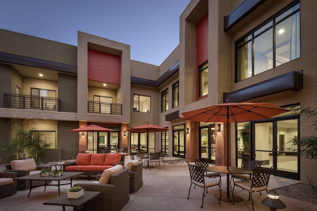 A modern residential courtyard with outdoor seating and patio umbrellas at dusk.