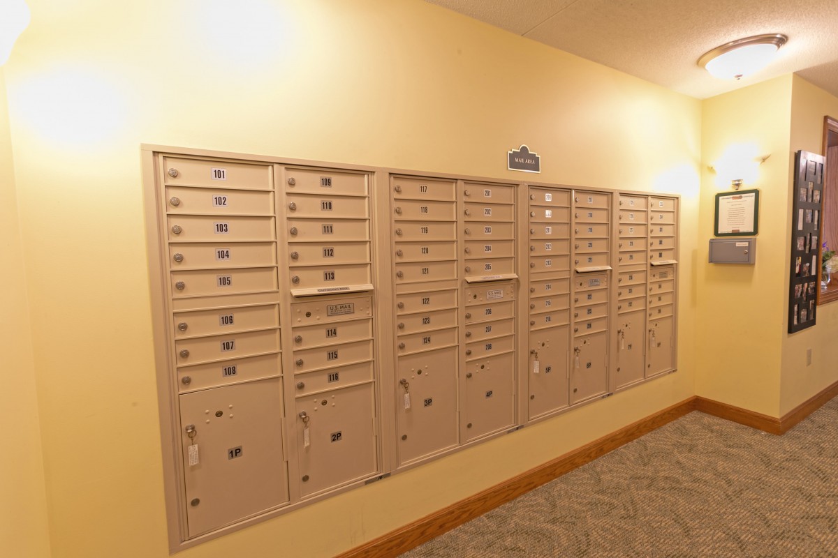 A row of mailboxes in an apartment building hallway.
