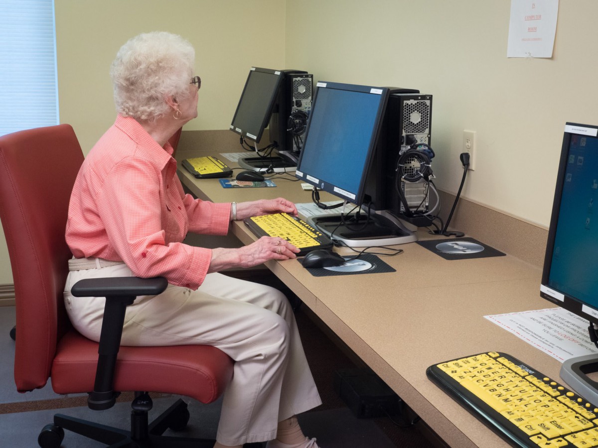 An elderly person using a computer at a workstation.