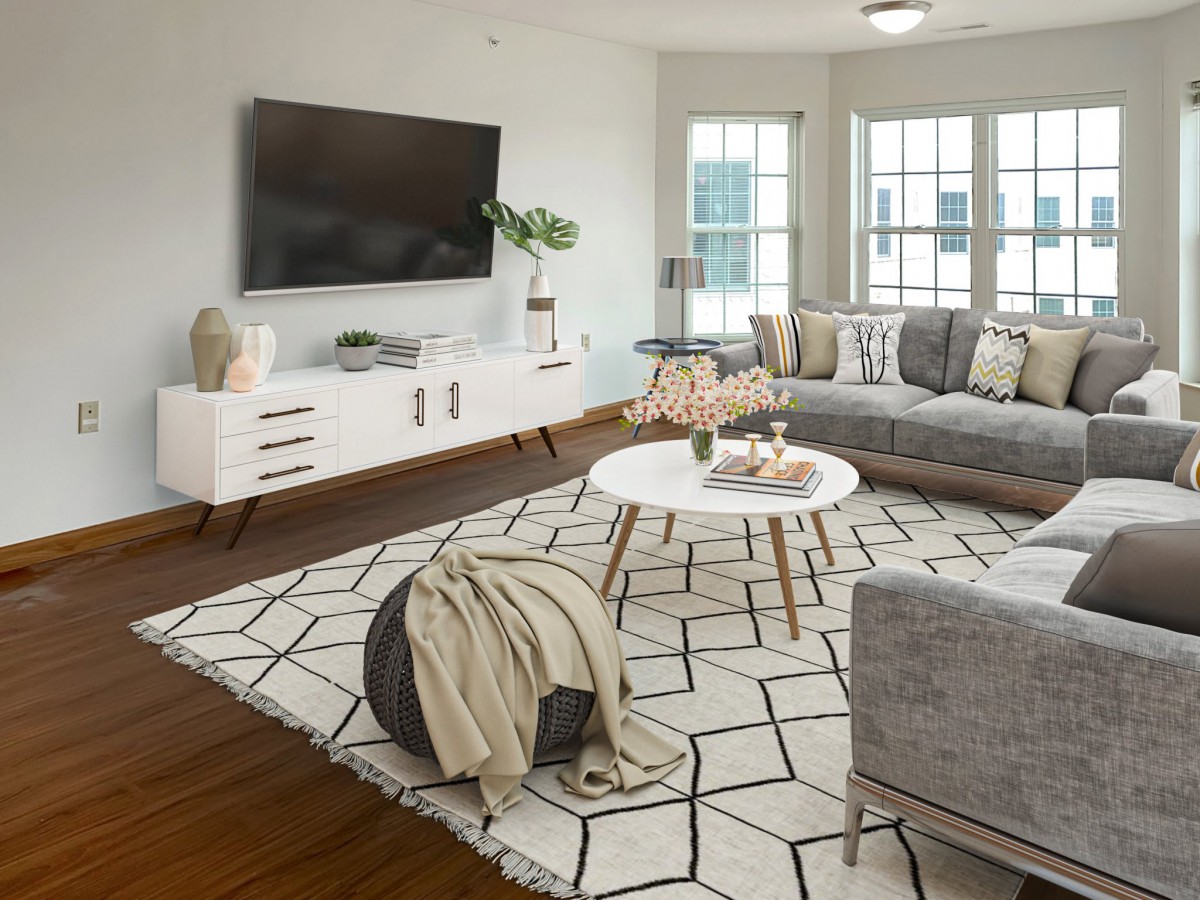 A modern living room featuring a large gray sofa, geometric rug, and sleek white furniture.