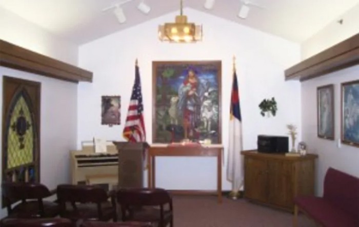 Interior view of a small chapel featuring flags and religious artwork.