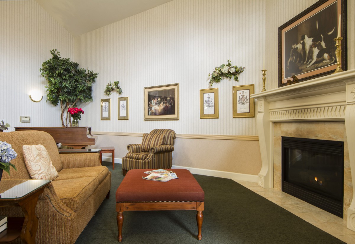 A cozy living room featuring a comfortable sofa, armchair, and a fireplace adorned with artwork and decor.