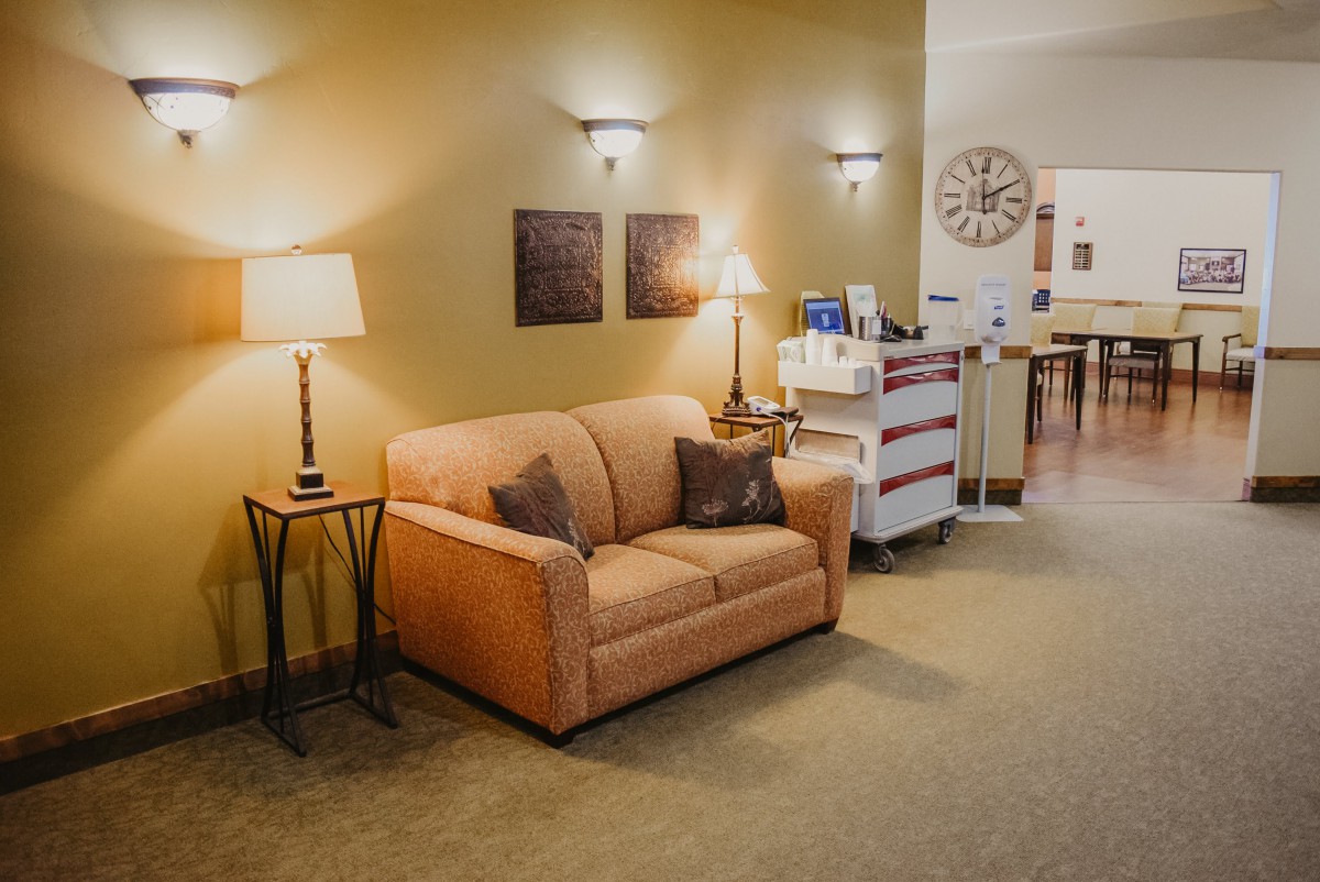 A cozy living room with a sofa, lamp, and wall decorations.