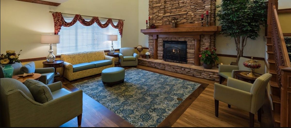 A cozy living room featuring a stone fireplace, comfortable seating, and a decorative rug.