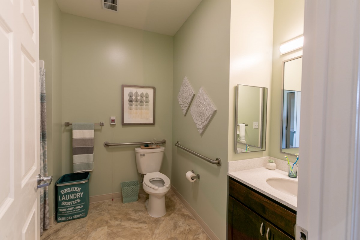 An accessible bathroom with a toilet, sink, and mirror.