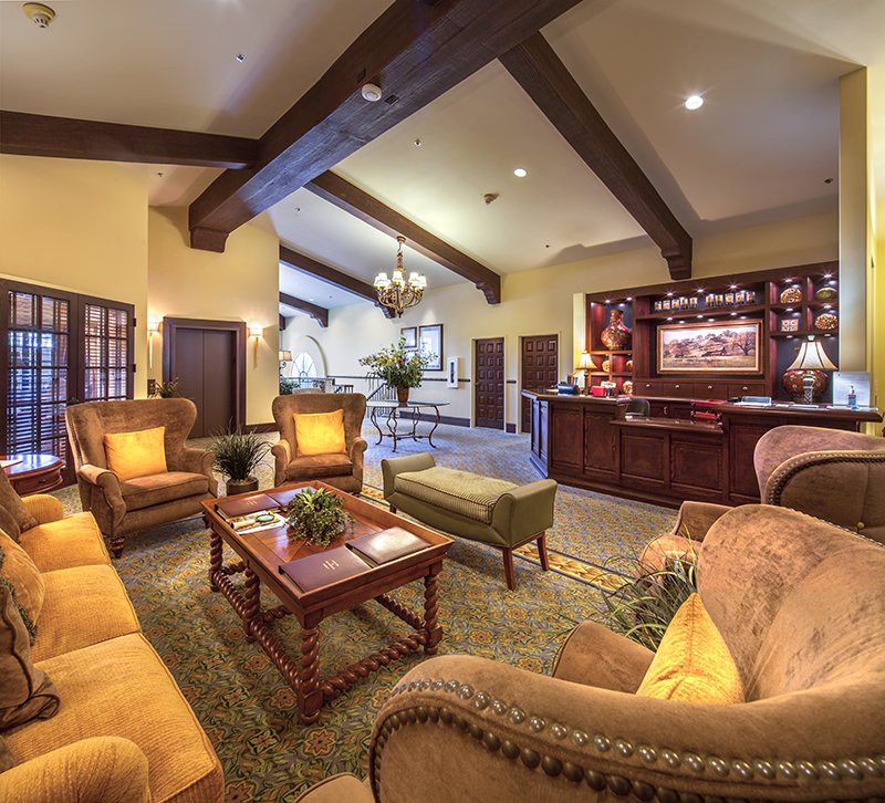 A cozy living room featuring warm lighting, comfortable seating, and elegant wooden beams.
