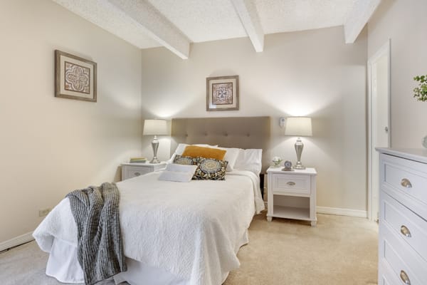 A cozy and modern bedroom featuring a neatly made bed, bedside tables, and elegant lamps.