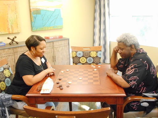 Two individuals engaged in a spirited game of checkers at a cozy indoor setting.