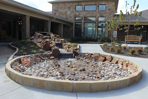A beautifully designed outdoor area featuring a stone fountain surrounded by landscaping.