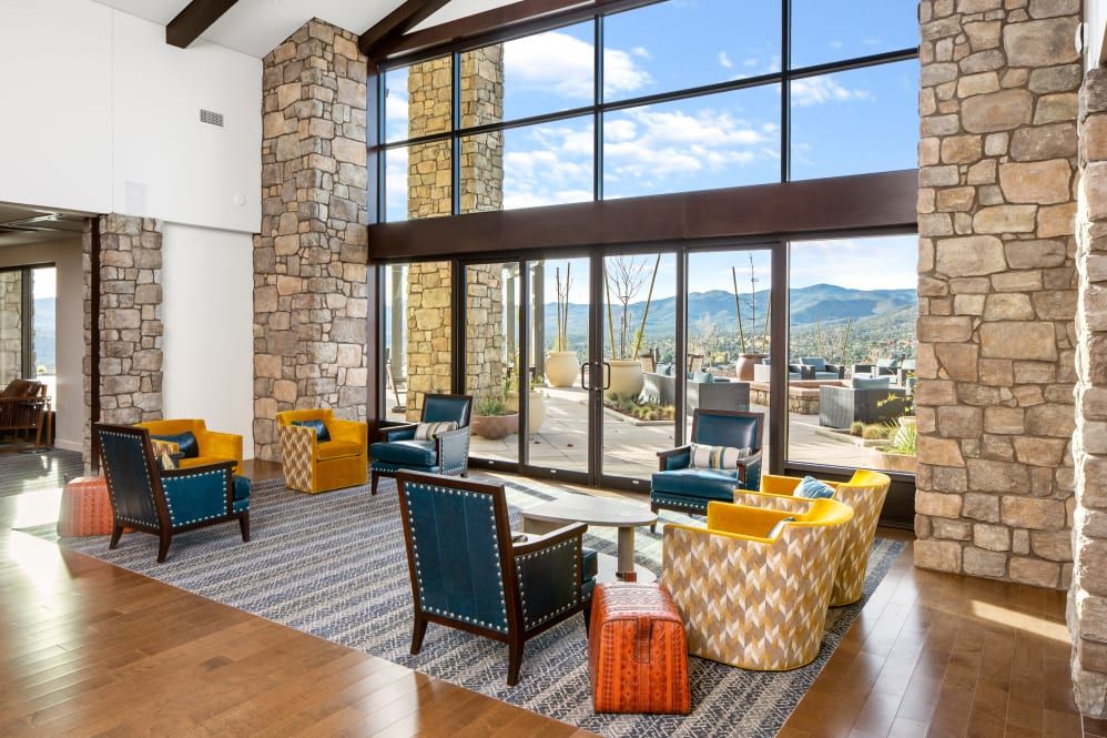 A modern living room with large windows offering a view of the mountains, featuring stylish furniture and ample natural light.