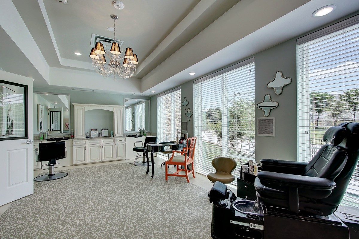 A modern salon interior with stylish chairs, large mirrors, and elegant chandeliers.