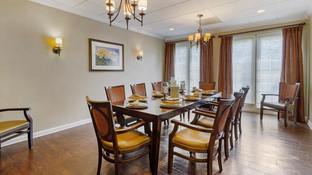 A well-decorated dining room with a large table, multiple chairs, and elegant lighting fixtures.