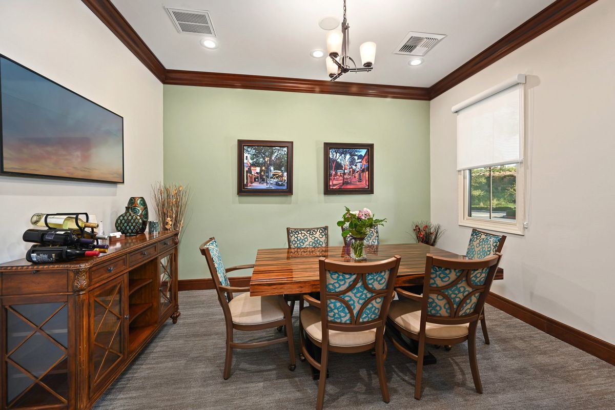 A well-appointed dining room featuring a wooden table and chairs, decorative artwork on the walls, and soft lighting.