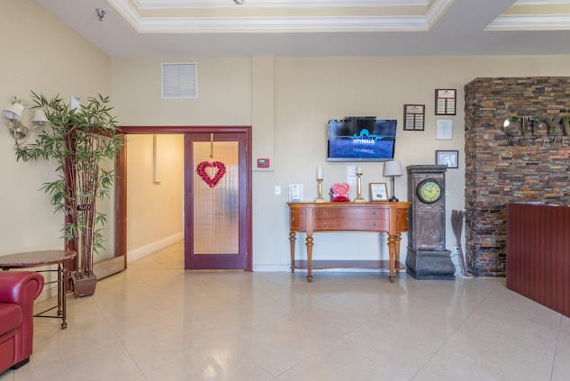 A welcoming lobby area featuring a heart decoration on the door, with a table, television, and decorative frames.