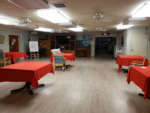 A spacious indoor area set up with red tablecloths, ready for an event.