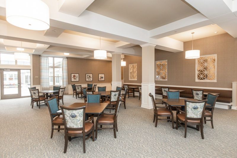 A modern dining area with neatly arranged tables and chairs, featuring elegant lighting and decor.