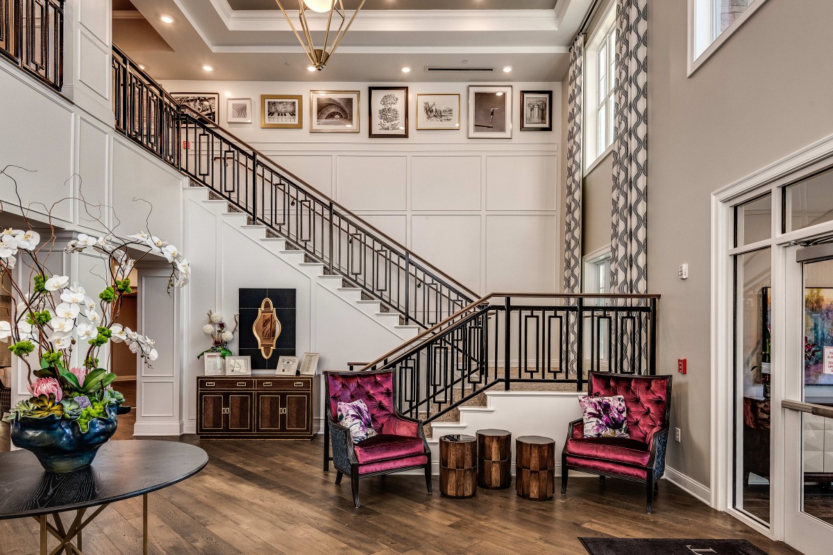 Elegant living space with a staircase, vibrant seating area, and framed artwork.