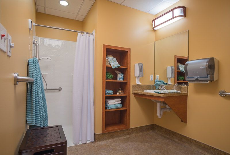 A clean and organized bathroom with a shower, sink, mirror, and shelves stocked with towels.