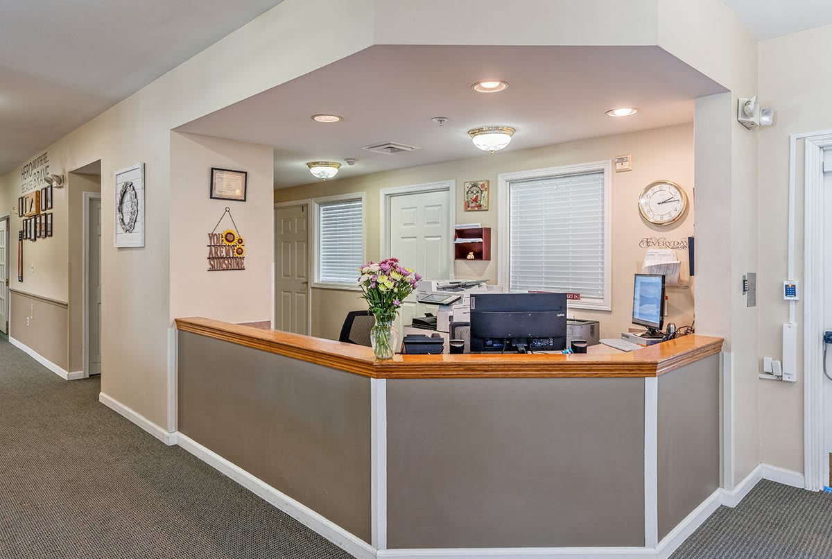 A welcoming reception area featuring a front desk with office equipment and fresh flowers.