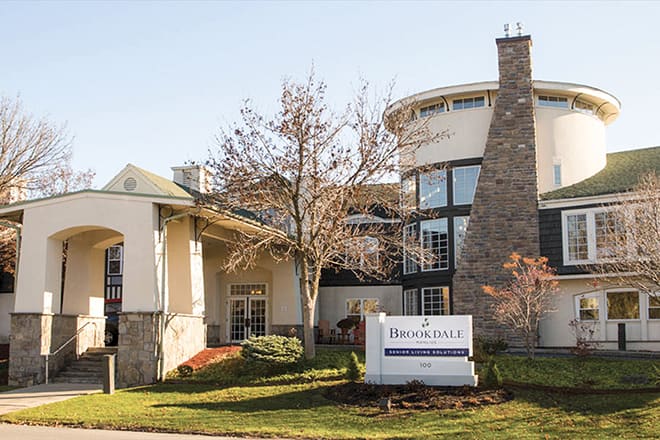 A hotel building featuring modern architecture with a stone chimney and surrounding trees.