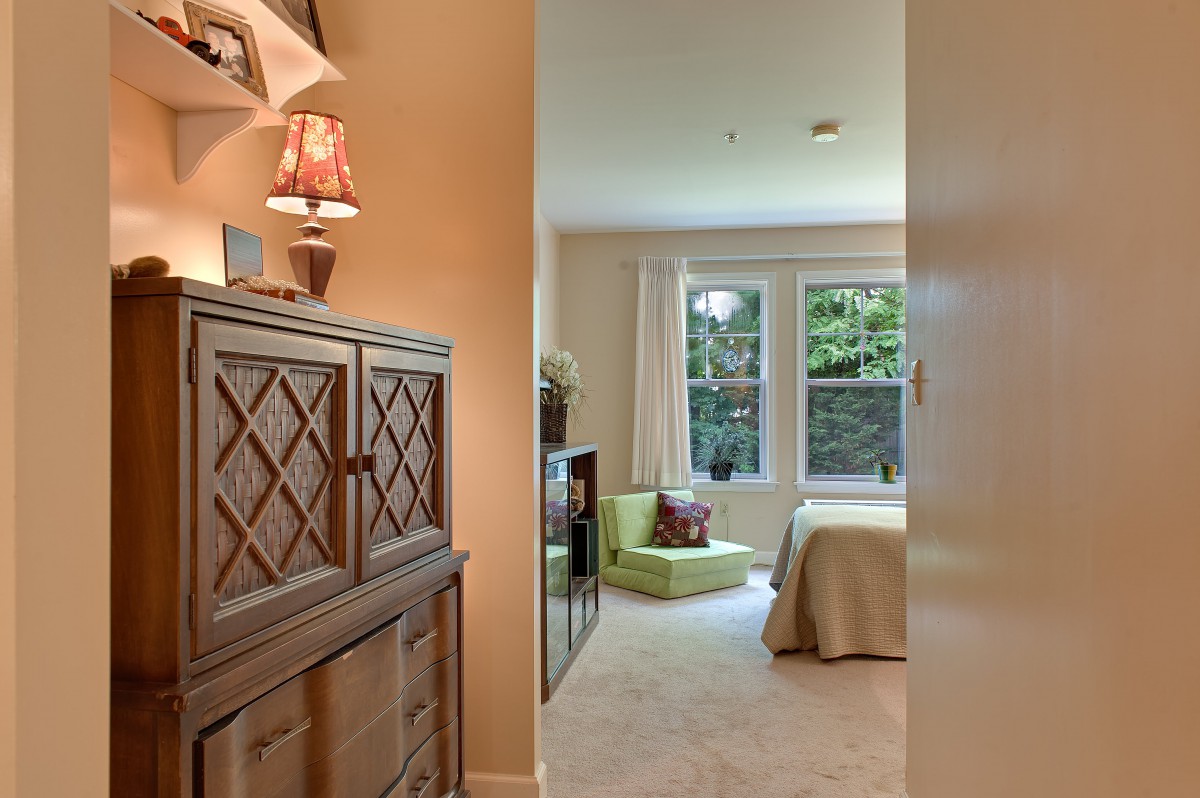 A cozy bedroom with natural light streaming in through a large window, showcasing elegant furniture and decor.