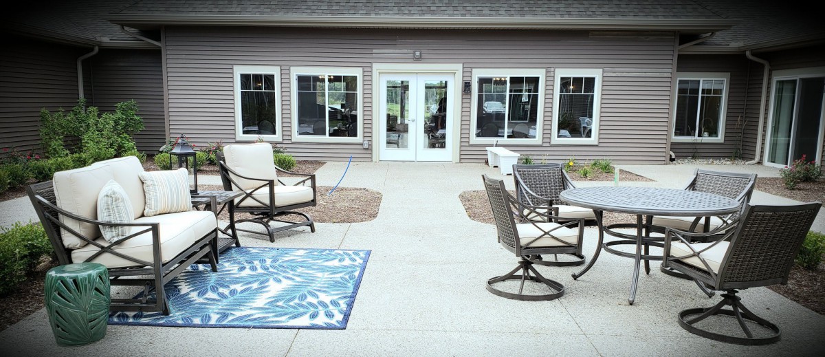 A cozy outdoor patio area with seating and a decorative rug.